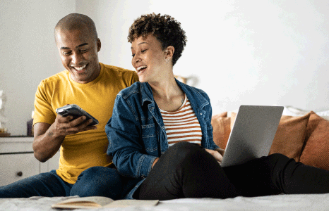 A man and a women looking at a laptop and mobile device.